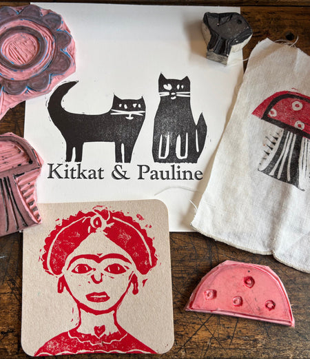 Collection of hand-stamped fabric and paper with various designs on a wooden surface.
