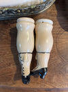 Pair of white and black ceramic shoes on a wooden surface