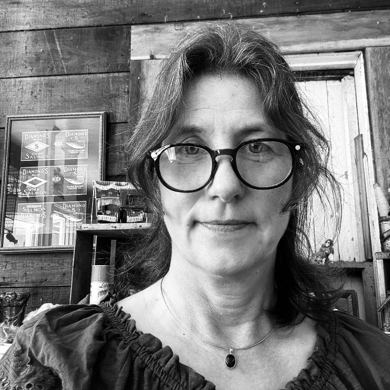 Black and white photo of a woman with glasses in a rustic setting
